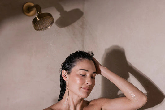 Smiling woman in a shower washing her healthy hair