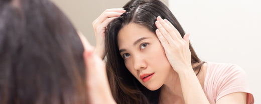 Young Asia woman looks at grey hair on her part