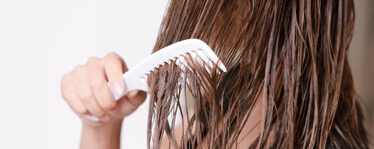 Woman combs tangles from wet hair caused by hard water hair damage 