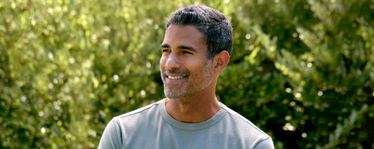 Man with grey hair in front of trees