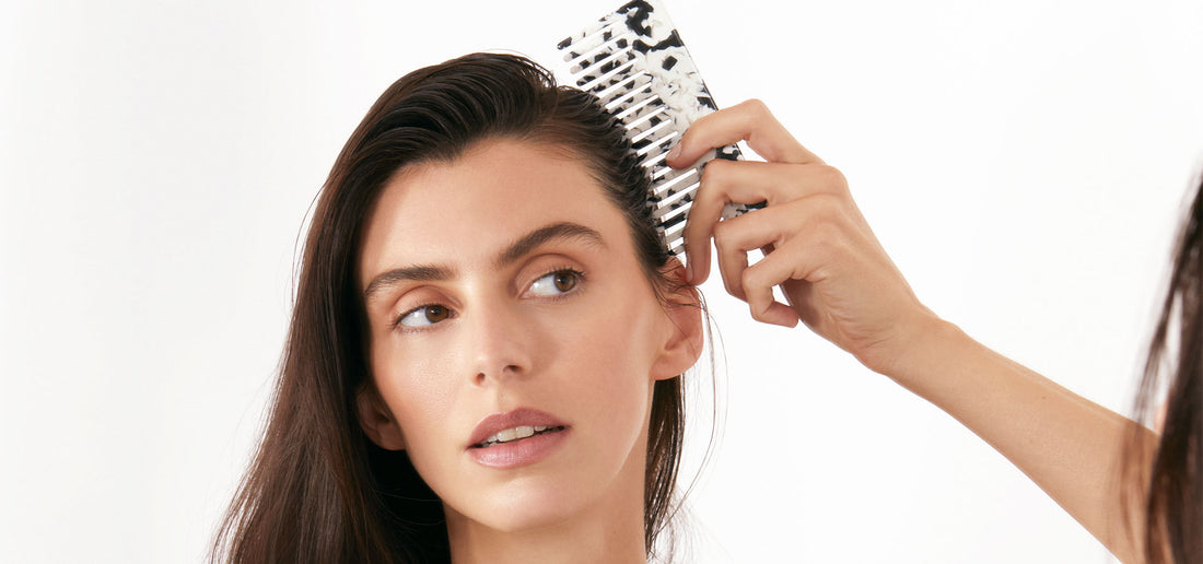 A woman safely detangles her hair with the Arey wide-tooth Comb $22