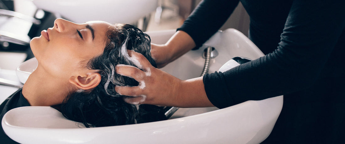 Stylist gives scalp detox massage to woman in salon