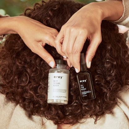 An image of a woman with healthy curly hair holding The System